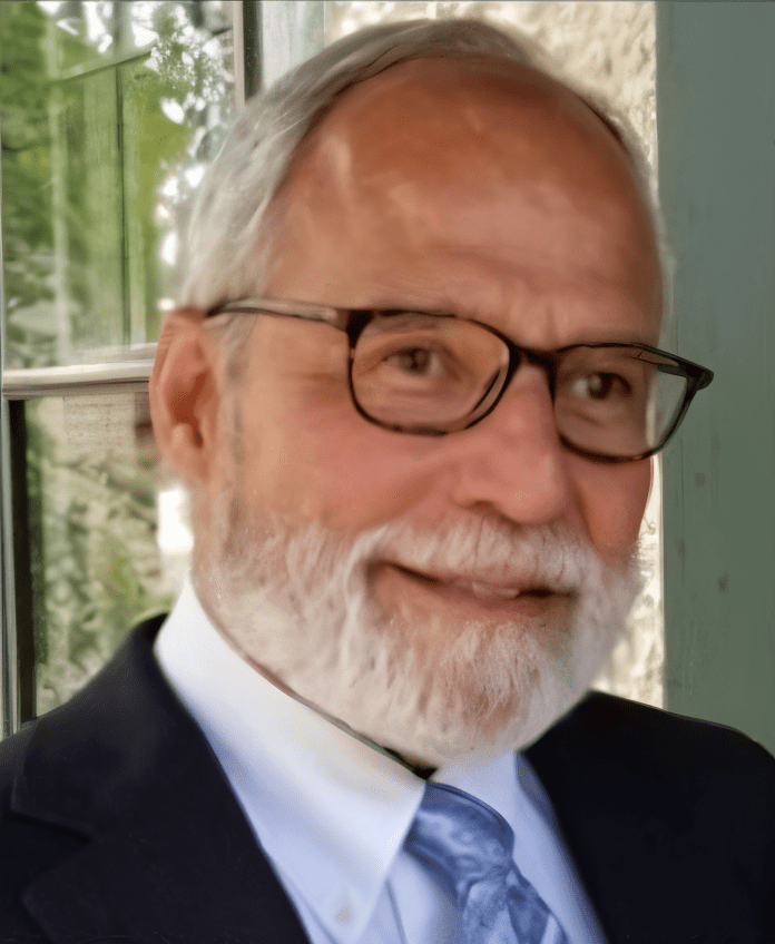 Smiling man with glasses and white beard.