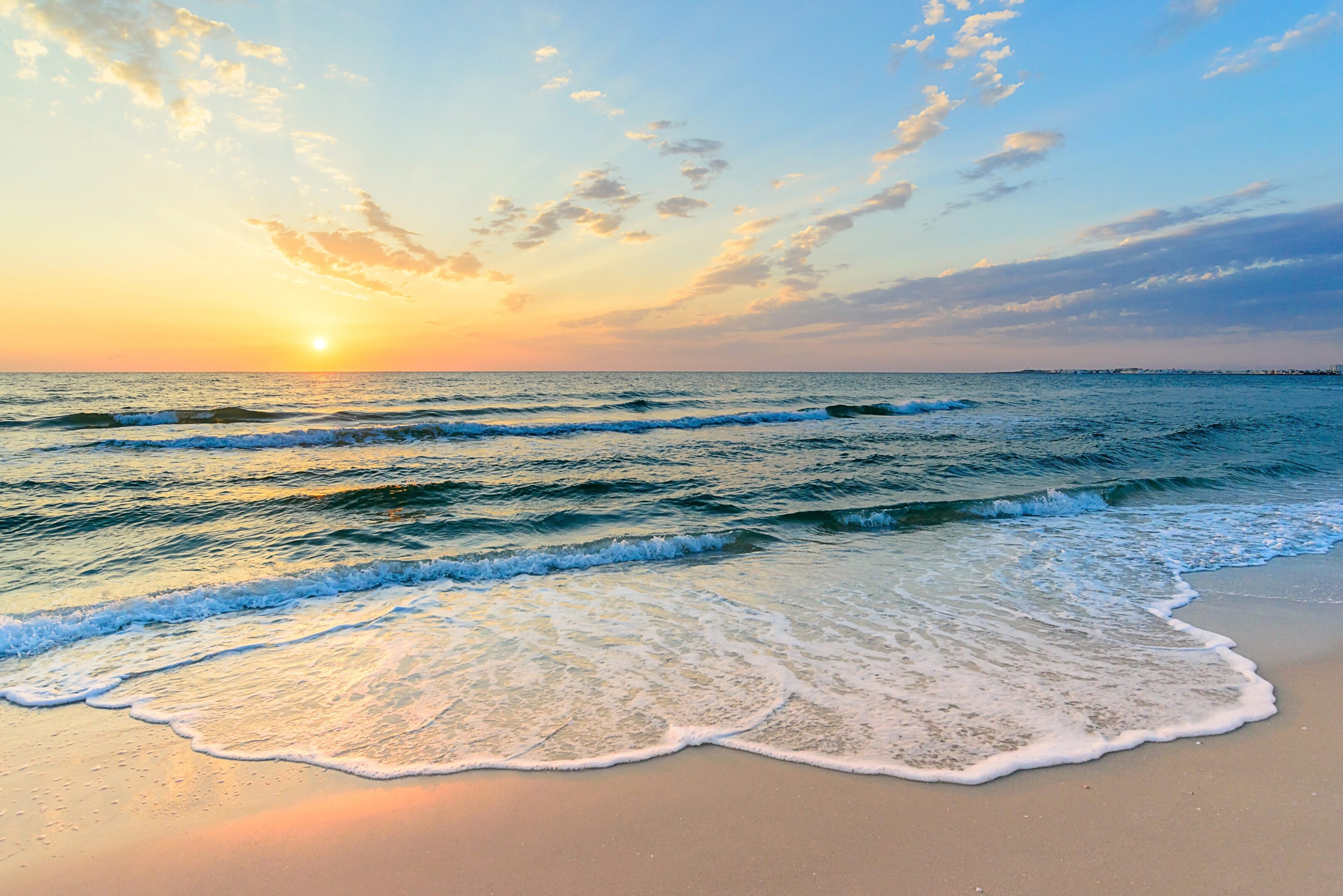 Sunset over gentle ocean waves and beach.