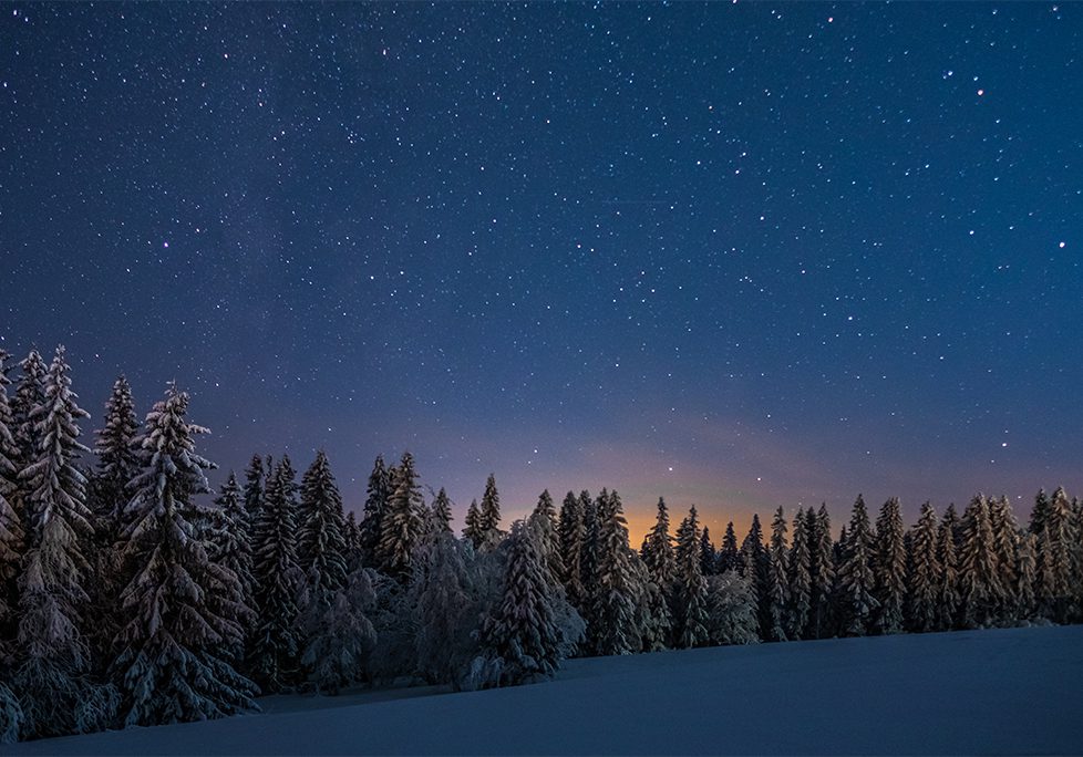 A night sky with stars and the moon in the background.