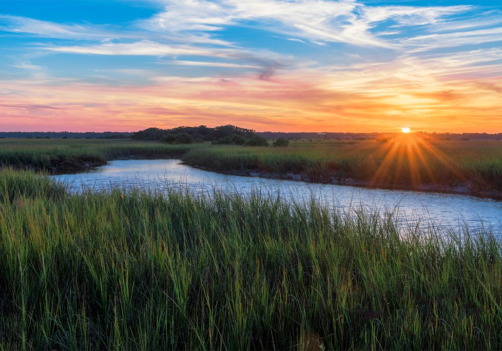 _0009_GettyImages-1095759454 A sunset over the water and grass.