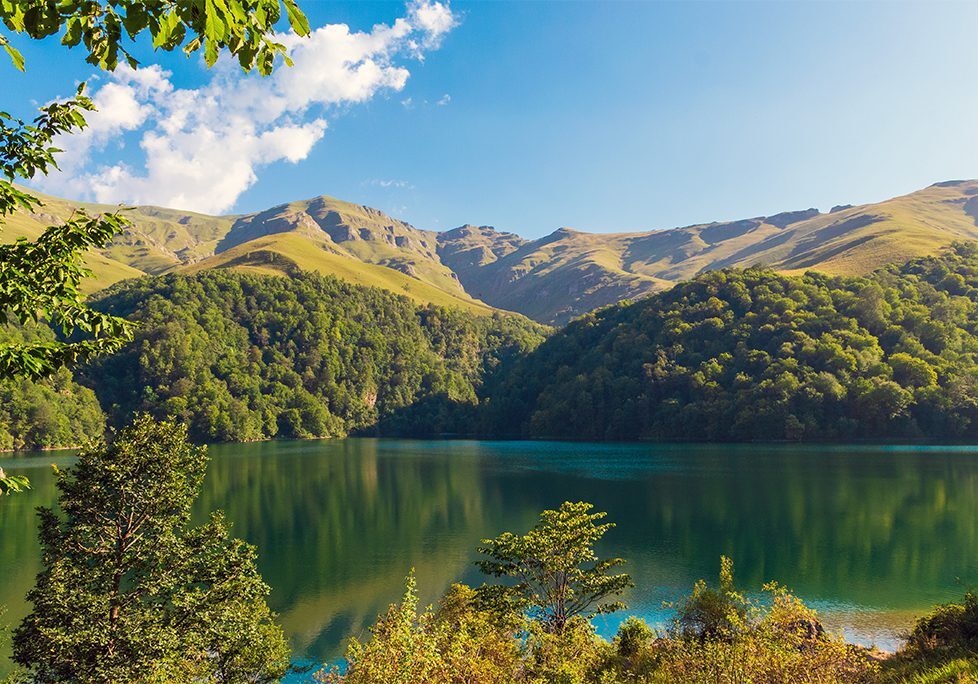 _0001_GettyImages-1981777041 A lake surrounded by mountains with trees in the foreground.