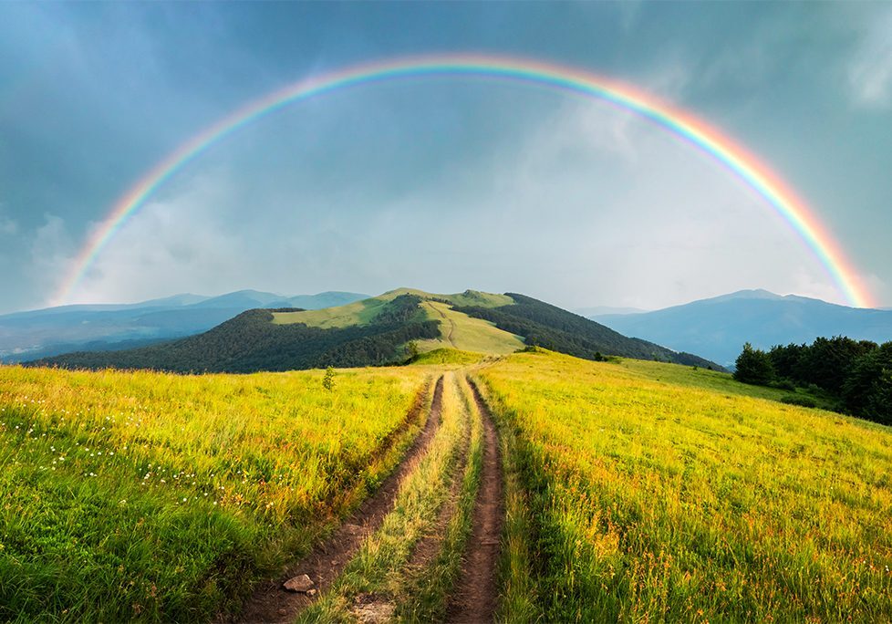 A rainbow over the top of a hill