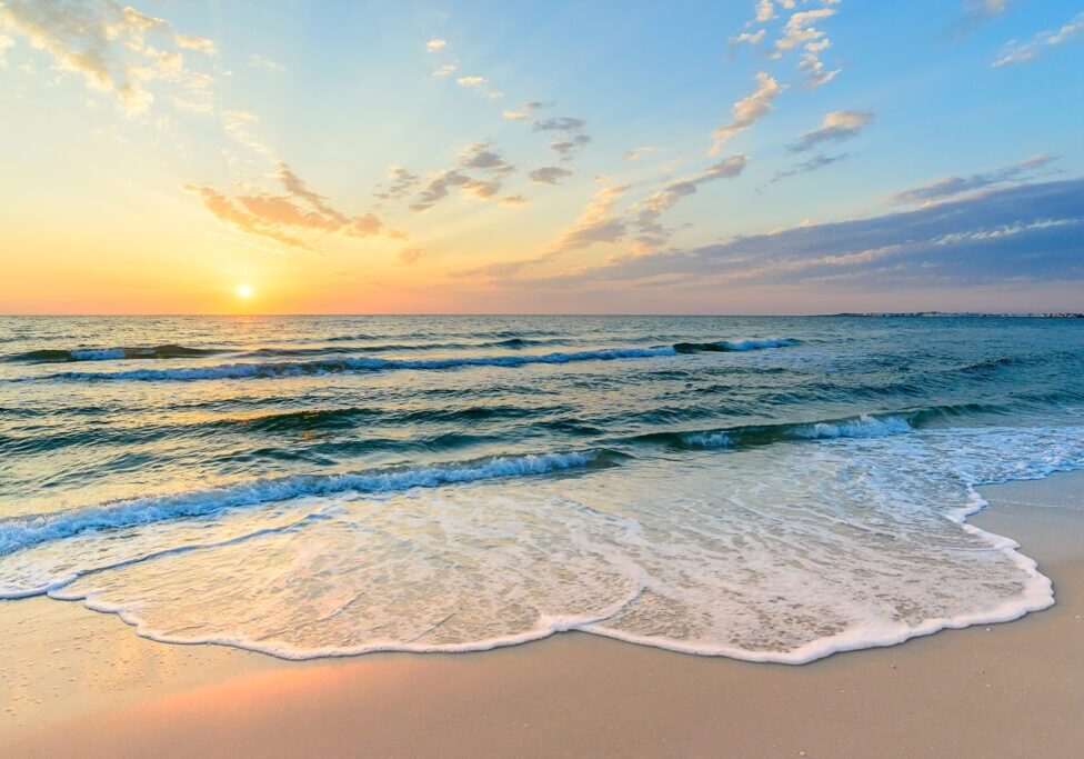 Sunset over gentle ocean waves and beach.